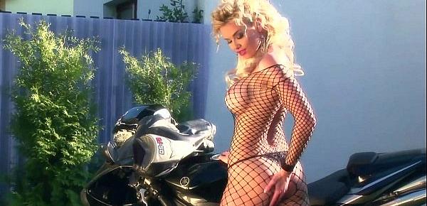  Busty blonde teases on a motorcycle in fishnet
